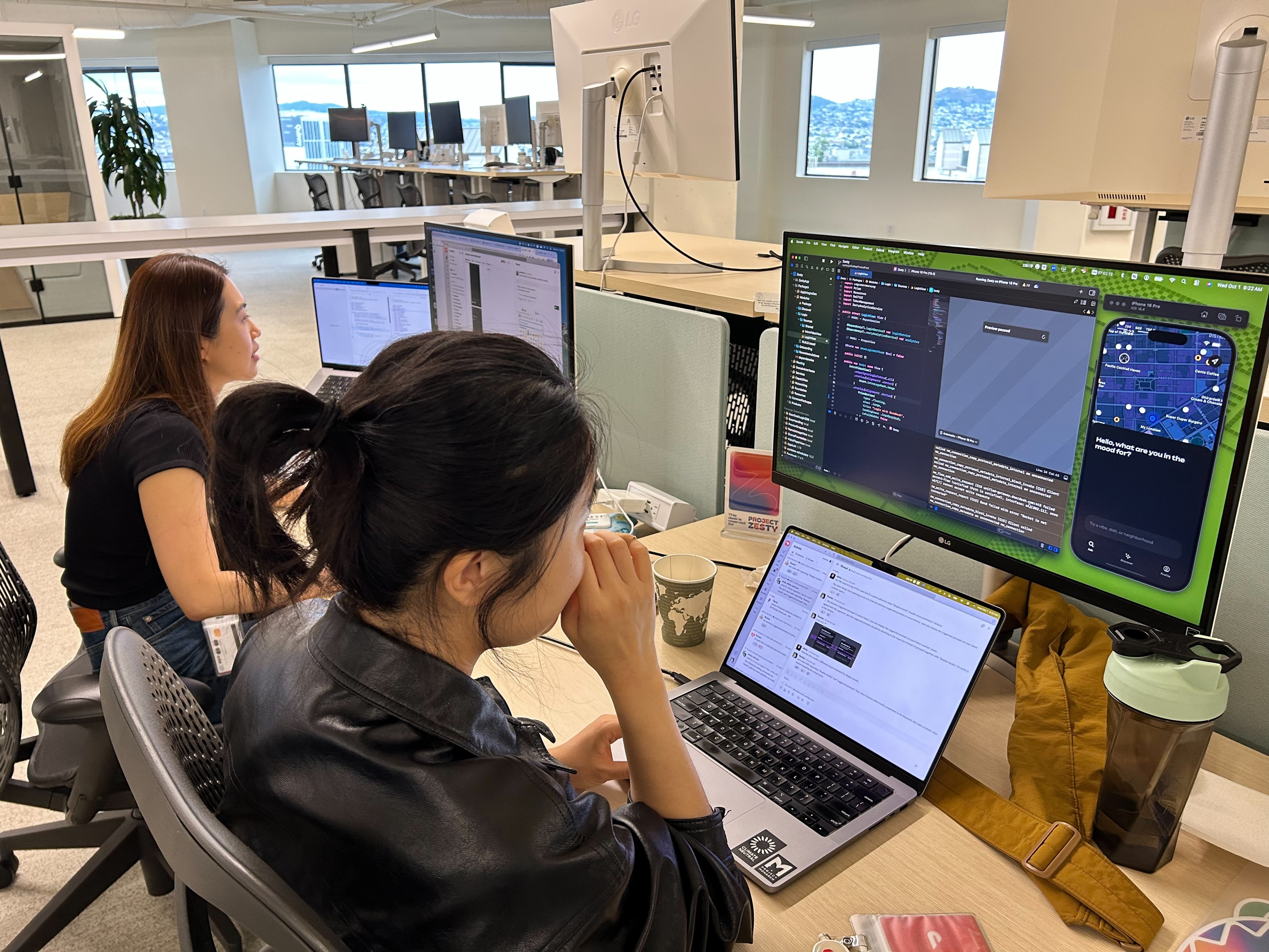 Desk with monitors showing code editor and Zesty app preview in context